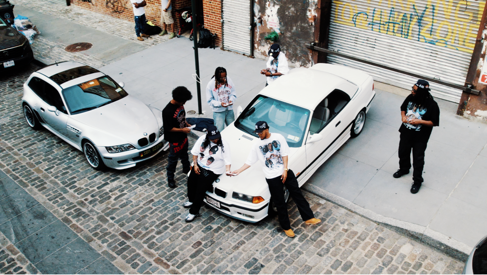 Aerial view of the crew between two white BMWs on cobblestone
